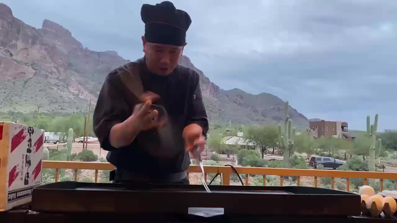 Hibachi chef cooking in a backyard with mountains in the distance